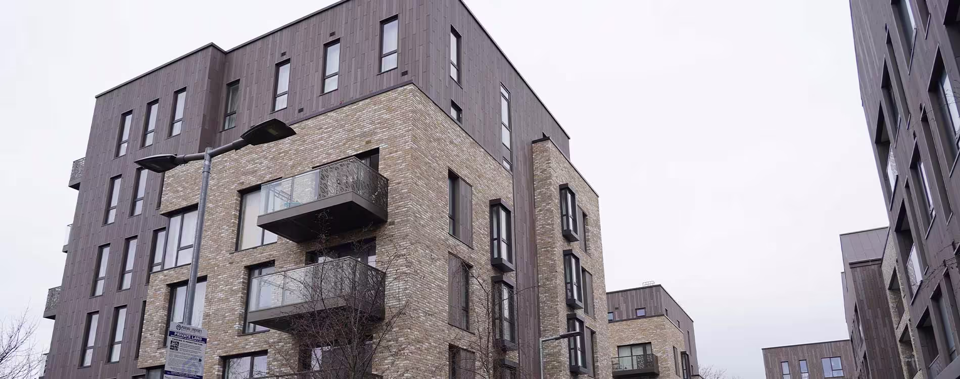 The modern exterior of a multi-storey residential block, featuring a mix of light brickwork and dark cladding, which has undergone an internal communal decorations project.