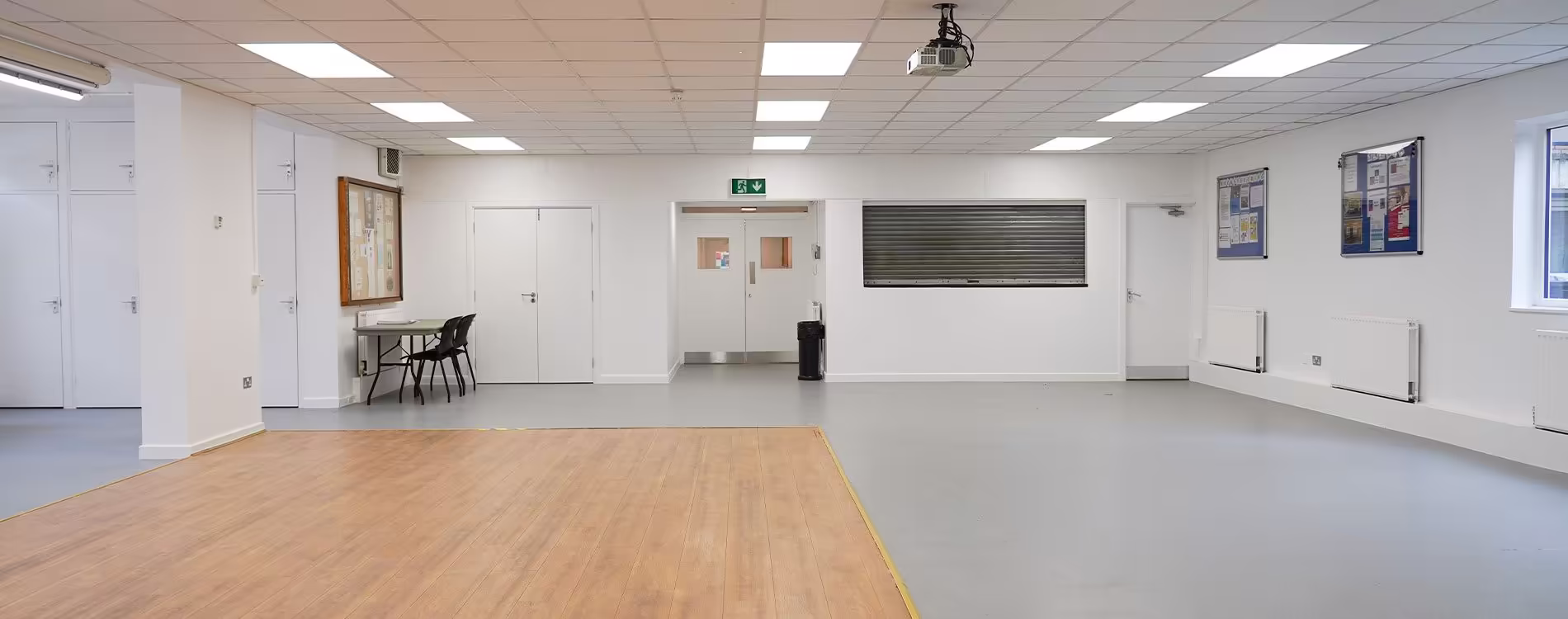 The large, multi-purpose main hall of a community centre after a full renovation, featuring a new wooden dance floor, fresh white walls, and modern lighting.