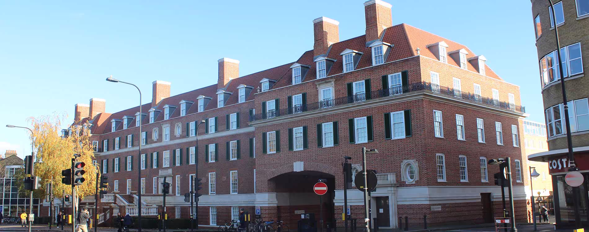 The grand, red-brick exterior of a large, historic London residential building after a cyclical maintenance programme, showing its many windows and architectural features.