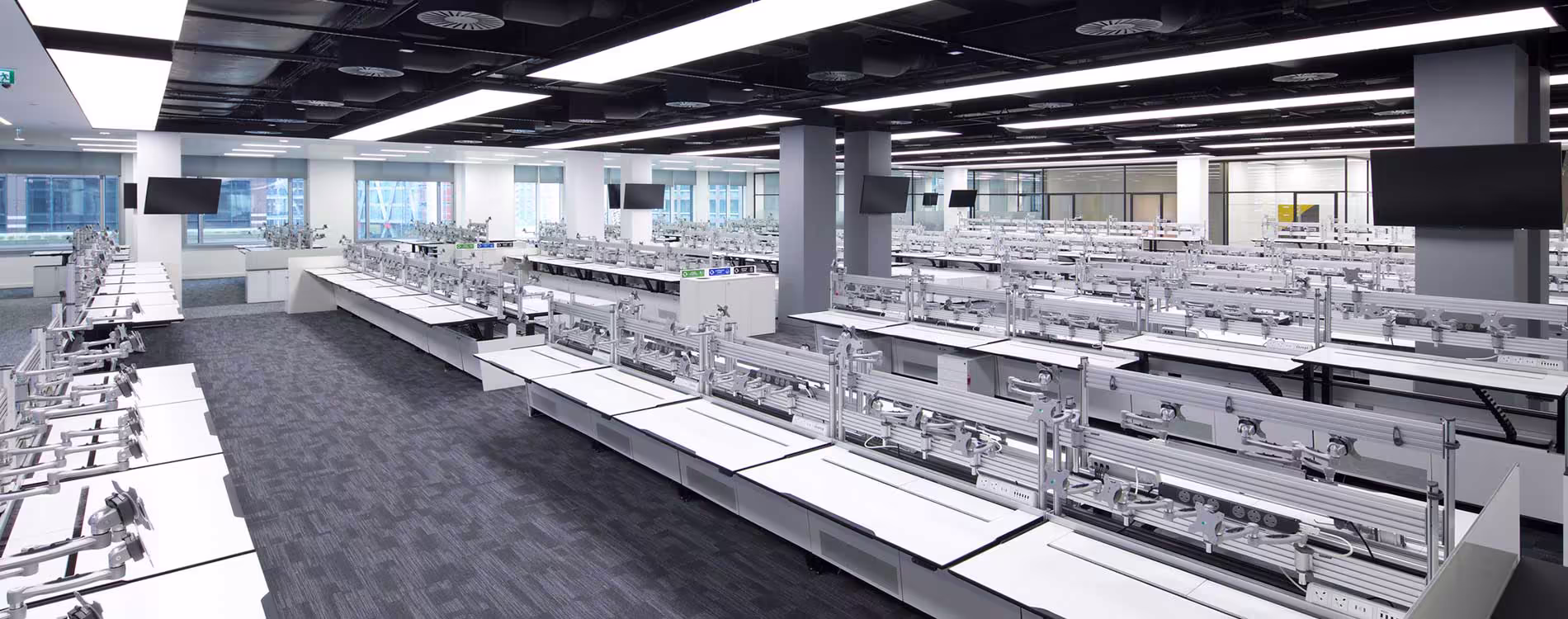 A large, modern office space after a data suite removal, showing vast rows of empty, specialized desk frames with all computer equipment and chairs cleared out.