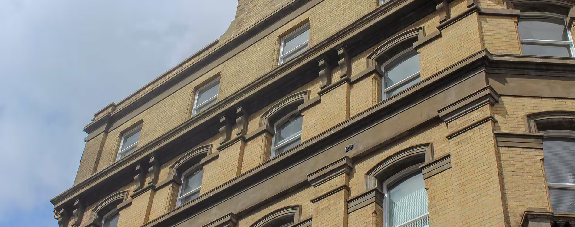 A low-angle view looking up at the beautifully renovated facade of a historic brick building, highlighting the clean lines of the restored stonework and window surrounds.