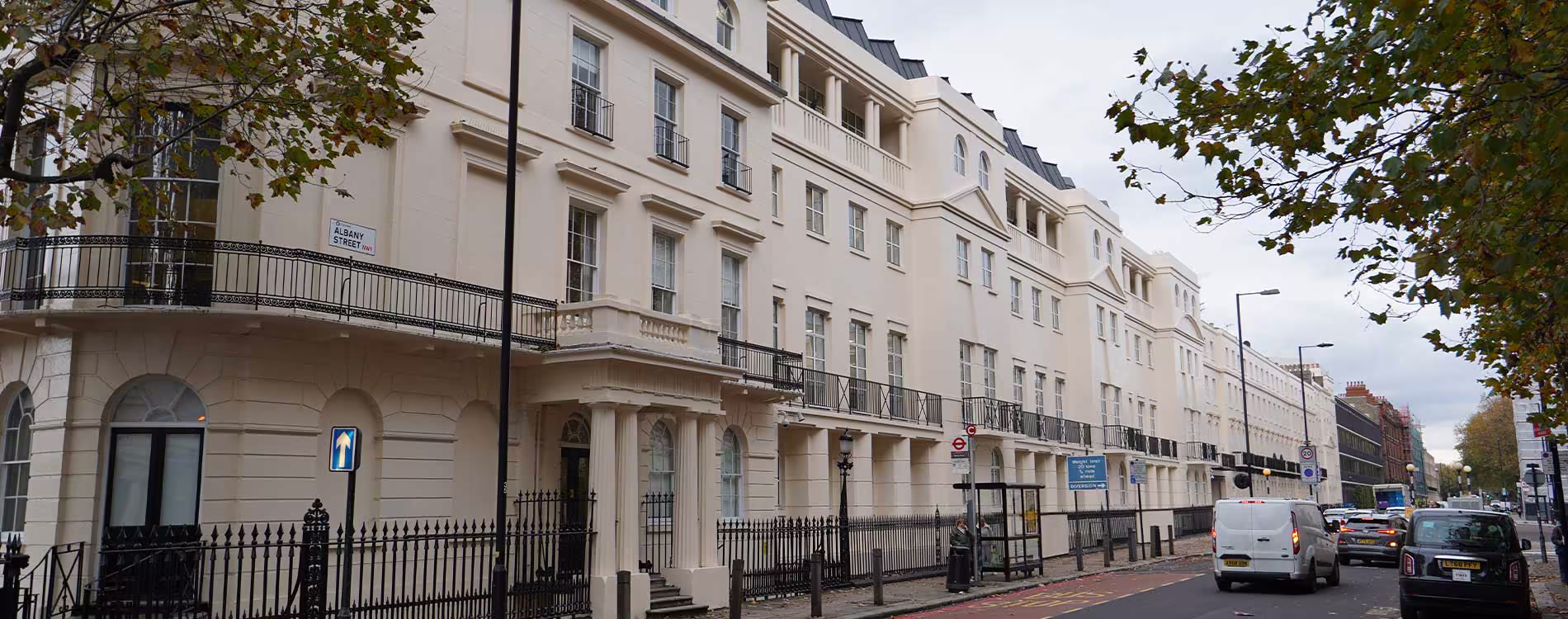 A panoramic view of a grand London terrace of classical buildings after a major external decoration works project, showing the pristine cream-coloured facades and black ironwork.