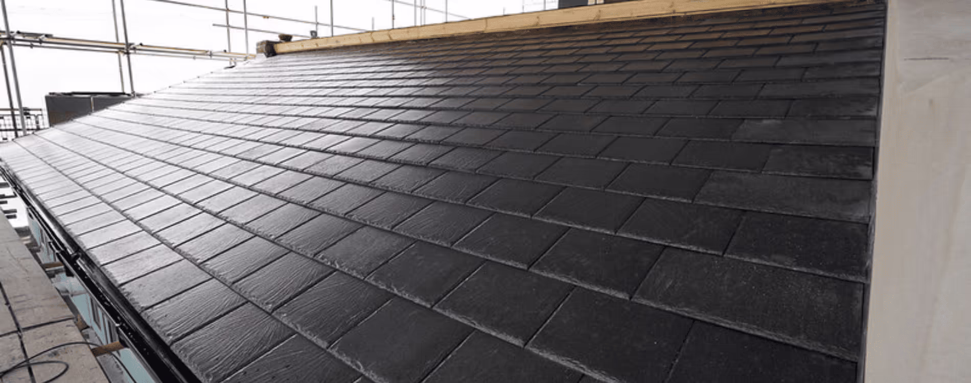 Close-up of a newly installed, pristine dark slate roof, showing the neat lines and quality workmanship of a flat renovation programme.
