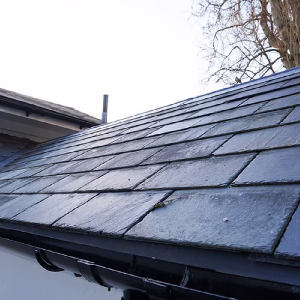 A close-up of the expertly laid new slate roof on the Grade II listed building, featuring clean lines and new black guttering as part of the heritage restoration.