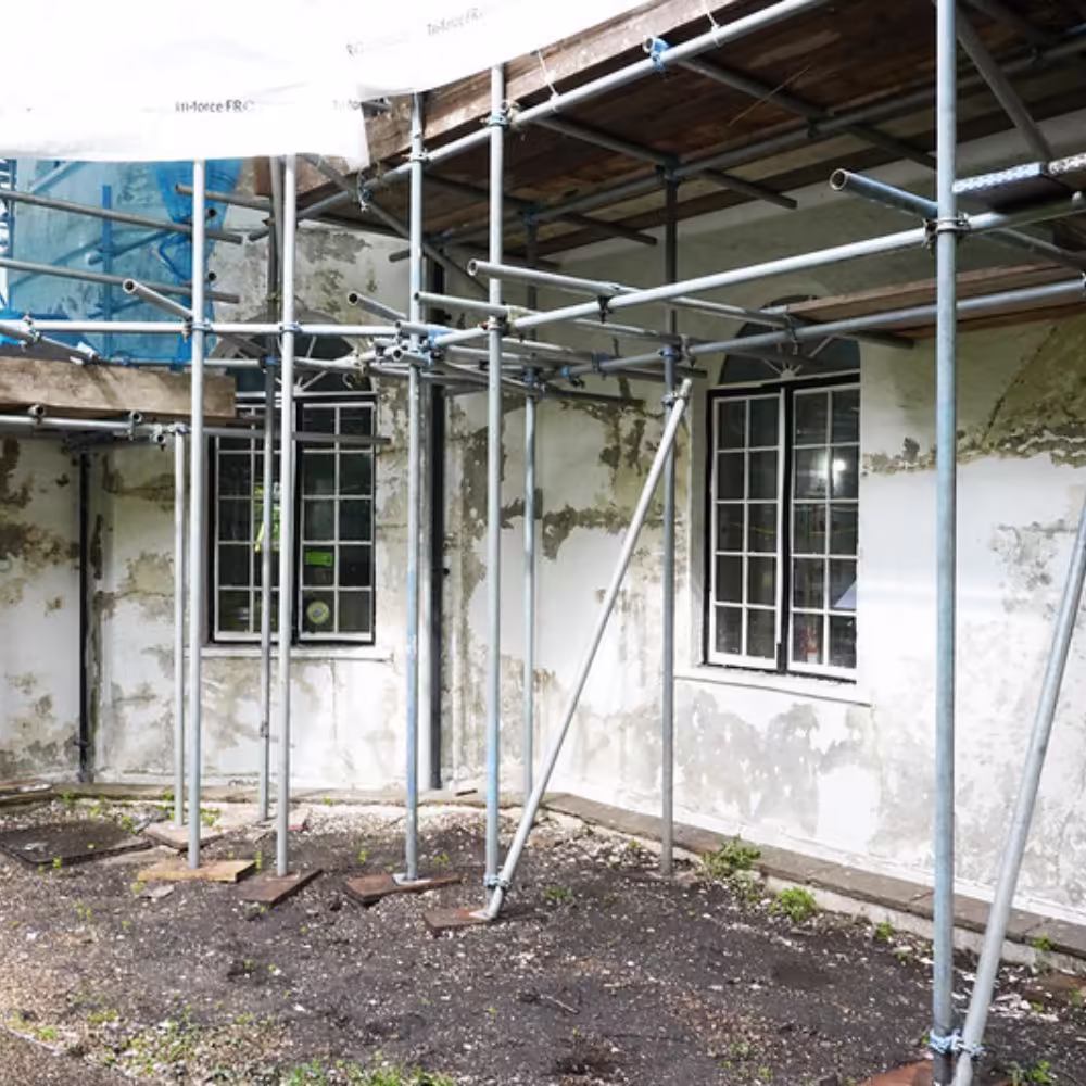 The exterior walls of the Grade II listed building during the refurbishment, showing the poor condition of the render with scaffolding in place for repairs.