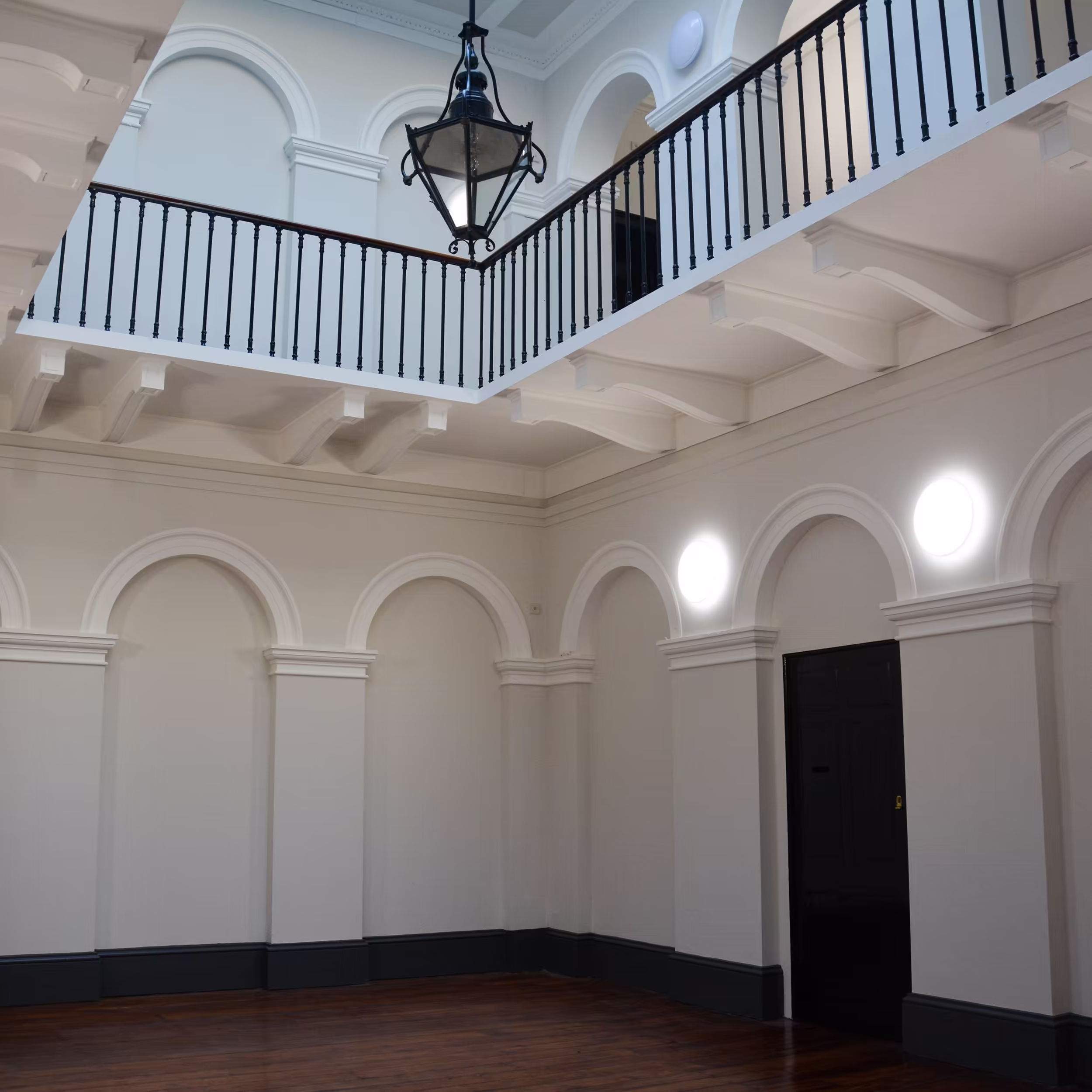 The magnificent double-height main hall of a Grade Listed building after repairs and redecoration, showing the mezzanine gallery and polished wood floors.