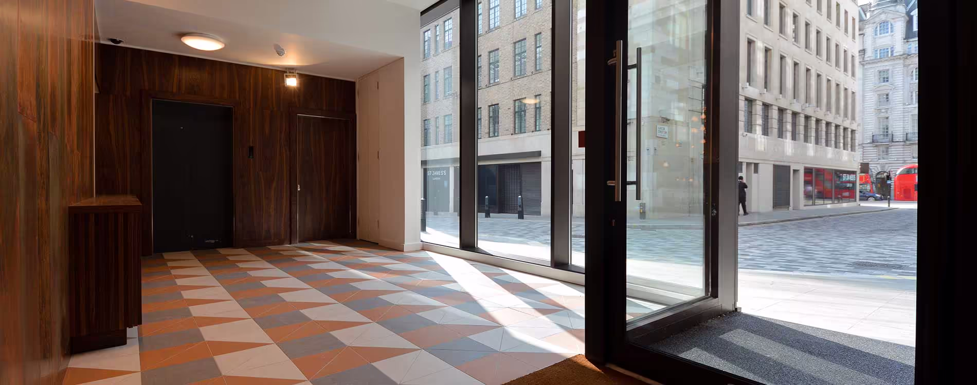 The bright, modern lobby of a refurbished commercial building, showing the new geometric tiled floor and large glass entrance looking onto a London street.