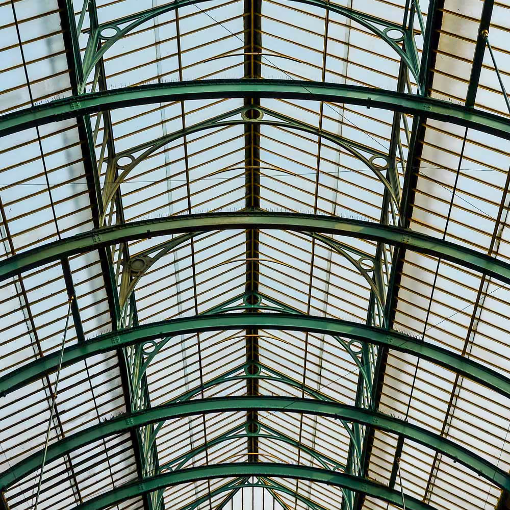 Architectural detail of the symmetrical, restored glass and iron roof of Covent Garden Market, showcasing the craftsmanship of the listed building.