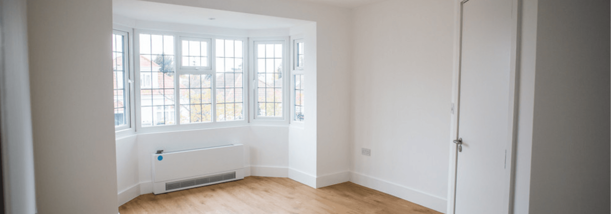 Inside a white room with windows and door. Wooden floor