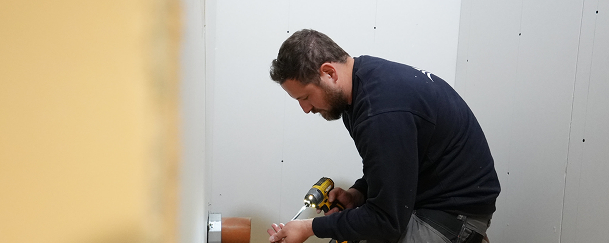 operative completing fire safety works in a white room wearing blue uniform