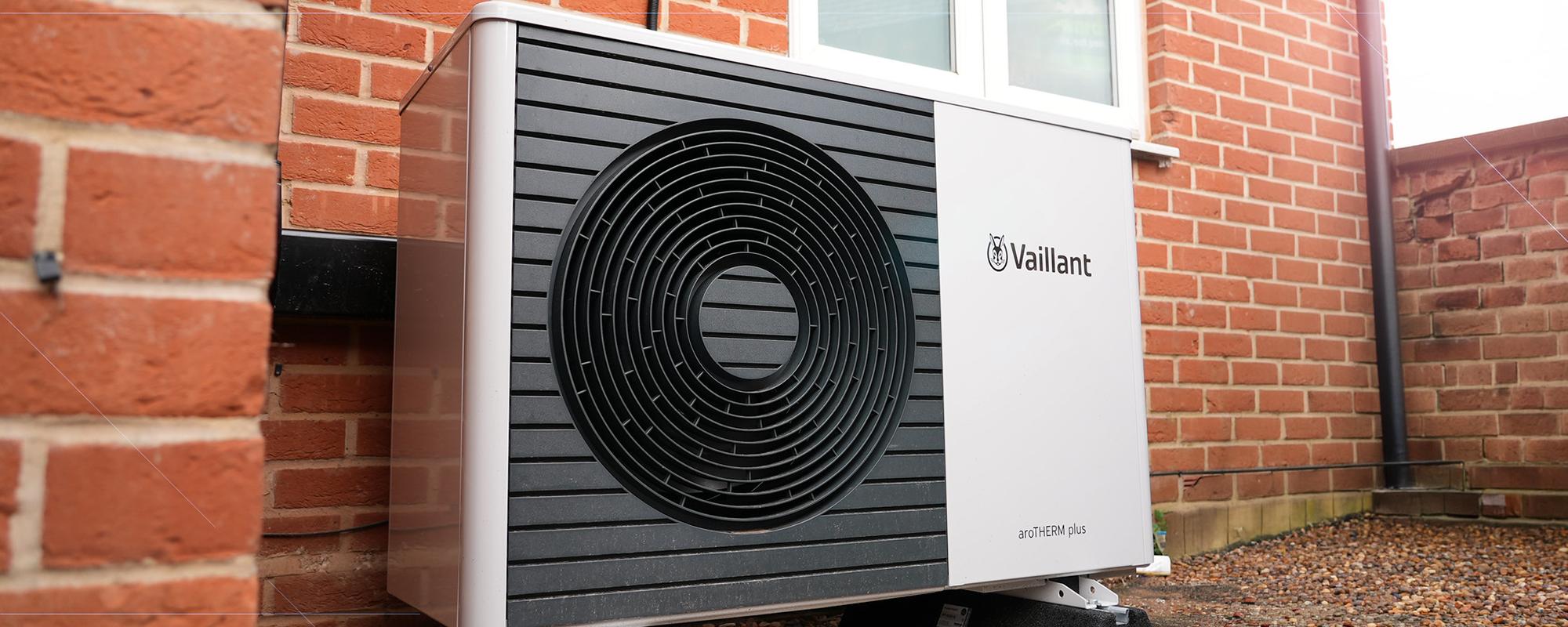 air source heat pump installed outside residential home against a brick wall