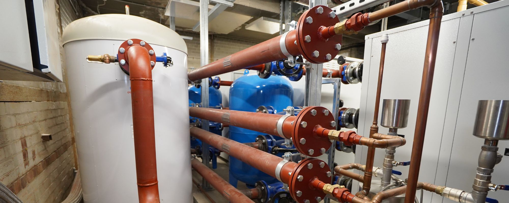 Plant room installation with white boiler and copper pipes
