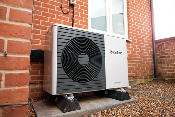air source heat pump installed outside residential home against a brick wall