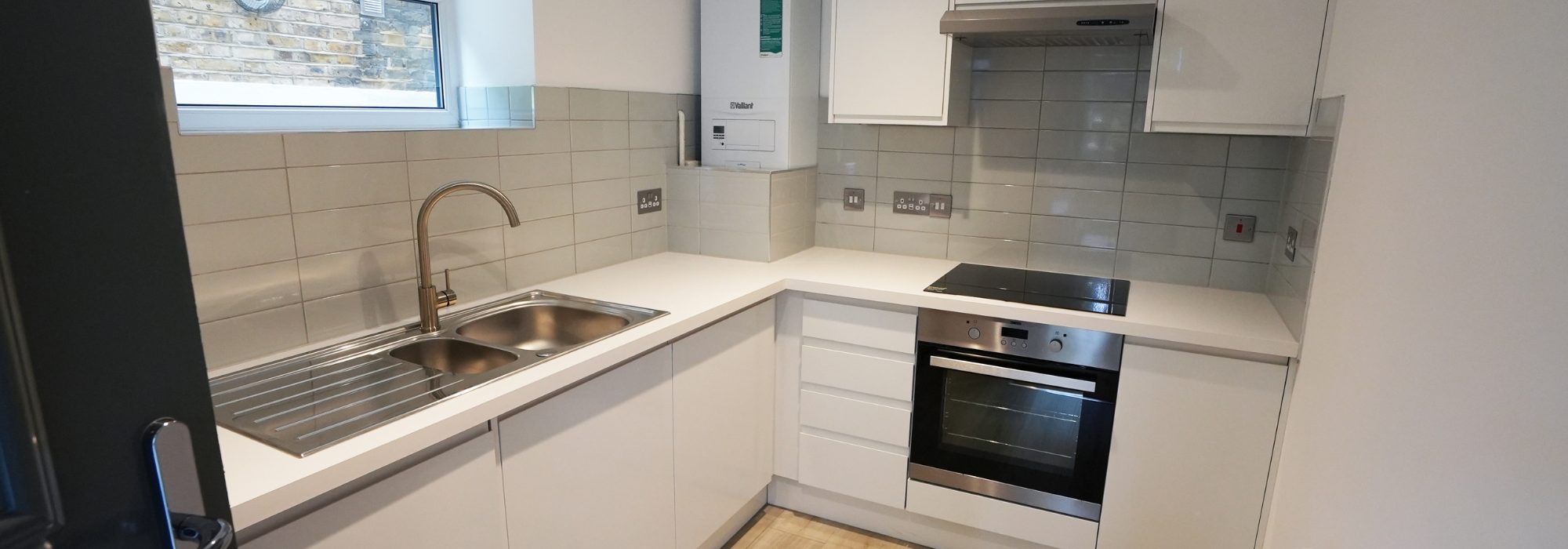 White kitchen cabinets and units with oven and sink, white horizontal tiles